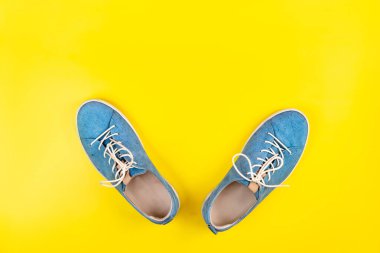 Mavi ayakkabılar izole edilmiş sarı arka planda duruyor.