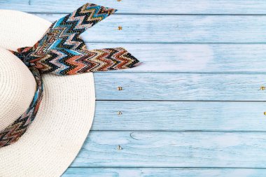 Mavi ahşap arka planda duran samandan beyaz bir şapkanın üst görüntüsü. Yaz tatili kavramı.