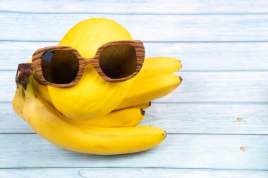 Sarı meyve ve bardakların bir çeşidi mavi ahşap bir arka planda yatıyor..