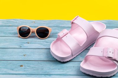 Yaz spor ayakkabıları ve gözlükleri izole edilmiş mavi ve sarı arka planda duruyor..