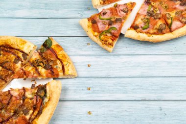 Mavi ahşap arka planda iki farklı lezzetli büyük pizza..