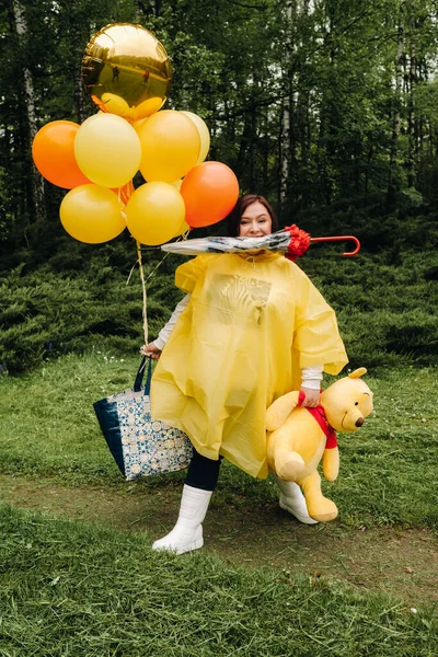 Eine Frau Gelben Regenmantel Hält Viele Verschiedene Dinge Den Händen — Stockfoto