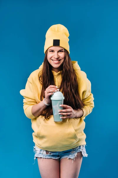 穿着黄色衣服 蓝色背景上有一杯果汁的怀孕女孩 — 图库照片