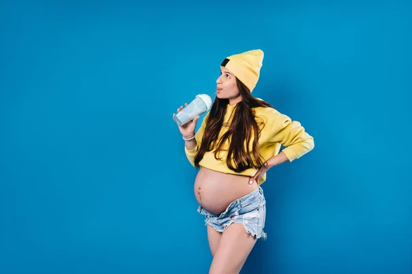 黄色の服に青い背景にジュースが入った妊婦さん — ストック写真