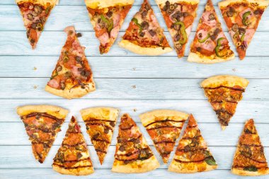 Mavi ahşap arka planda bir sürü lezzetli üçgen pizza dilimleri var..