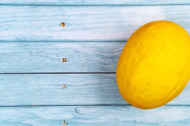 Tüm sarı kavun mavi ahşap bir zeminde uzanıyor..