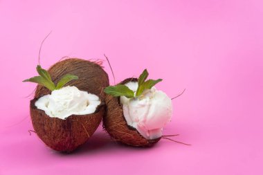 Pembe arka planda nane yapraklarıyla süslenmiş taze hindistan cevizli vanilyalı dondurma topları..