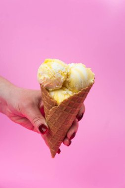 Bir el dondurma külahını bir gözleme bardağında pembe buzlu dondurmanın üstünde tutar.