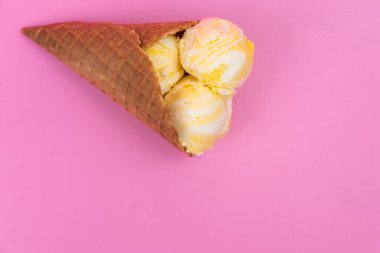 Pembe arka planda waffle külahında meyveli dondurma topları.