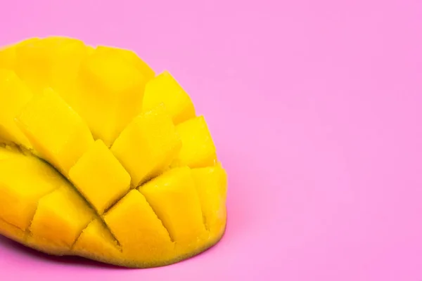 Fresh ripe mango on a pink background. Half a sliced mango on a pink background.