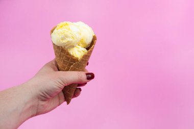 Bir el dondurma külahını bir gözleme bardağında pembe buzlu dondurmanın üstünde tutar.