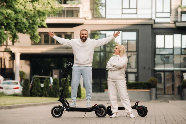 A couple in love in white clothes stands in the city on electric scooters..