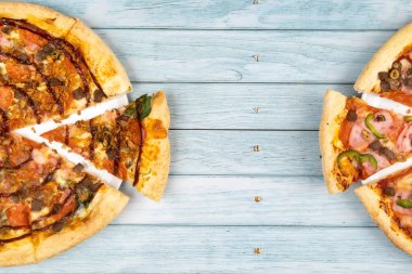 Mavi ahşap arka planda iki farklı lezzetli büyük pizza..