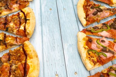 Mavi ahşap arka planda bir sürü lezzetli üçgen pizza dilimleri var..