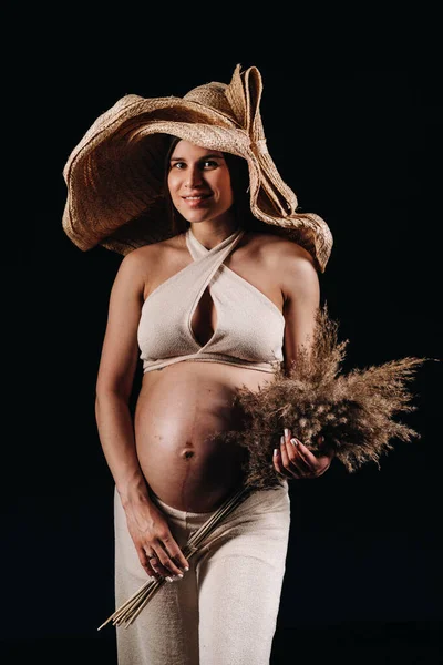 Těhotná Žena Slámě Klobouk Béžové Oblečení Kyticí Rukou Studiu Černém — Stock fotografie