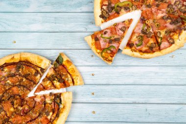 Mavi ahşap arka planda iki farklı lezzetli büyük pizza..