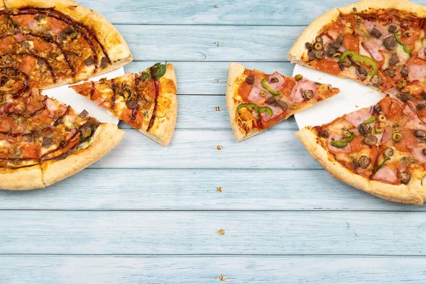 Mavi ahşap arka planda iki farklı lezzetli büyük pizza..