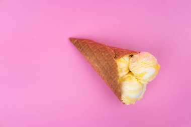 Pembe arka planda waffle külahında meyveli dondurma topları.