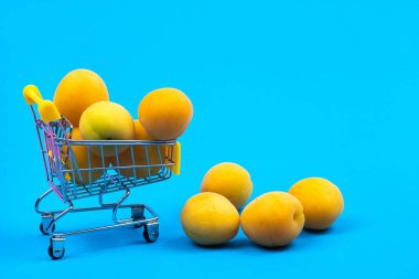 Mavi arka planda kayısısı olan bir alışveriş sepeti..