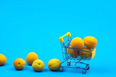 Mavi arka planda kayısısı olan bir alışveriş sepeti..