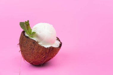 Pembe arka planda nane yapraklarıyla süslenmiş taze hindistan cevizli vanilyalı dondurma topları..