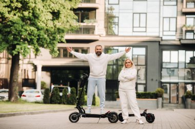 Beyaz elbiseli bir çift şehirde elektrikli scooterlarla duruyor...