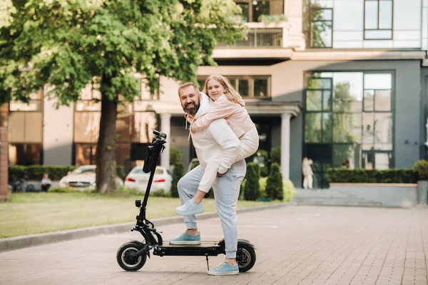 A family in white clothes stands in the city on electric scooters.Father and daughter on an electric scooter.