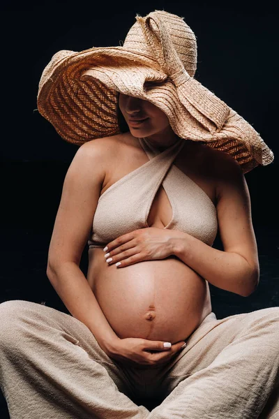 Pregnant Woman Straw Hat Sits Floor Beige Clothes Studio Black — Stock Photo, Image