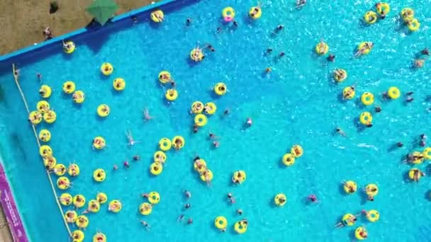 Ovanifrån av människor som kopplar av i poolen på gula uppblåsbara cirklar — Stockvideo