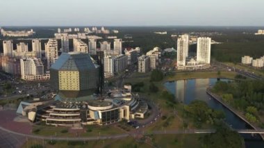Günbatımında Belarus Cumhuriyeti 'nin başkenti Minsk' te bir parka sahip olan Ulusal Kütüphane 'nin ve yeni küçük bölgenin en üst görüntüsü, bir kamu binası.
