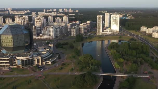 Bovenaanzicht van de Nationale Bibliotheek en het nieuwe microdistrict met een park in Minsk - de hoofdstad van de Republiek Wit-Rusland bij zonsondergang, een openbaar gebouw — Stockvideo