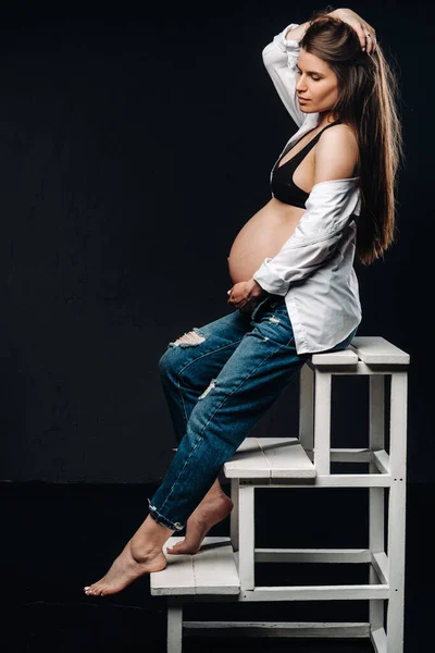 Mujer Embarazada Sentada Una Silla Escalera Estudio Sobre Fondo Negro — Foto de Stock