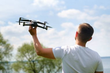 Elinde kuadrokopter olan bir adam, doğada gökyüzüne yükseldi..