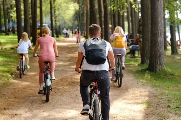 A group of cyclists with backpacks ride bicycles on a forest road enjoying nature.