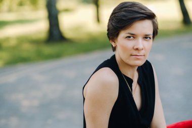 Parktaki sokakta duran kırmızı elbiseli bir kızın portresi..