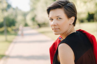 Parktaki sokakta duran kırmızı elbiseli bir kızın portresi..