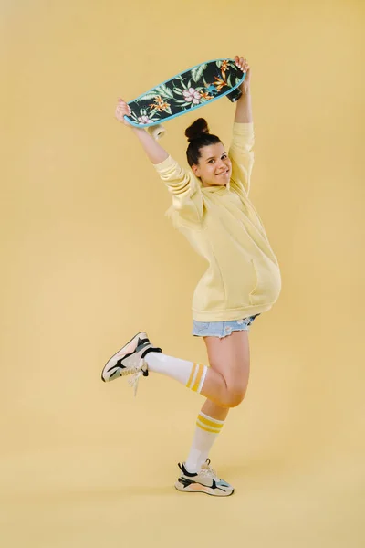 Zwanger Meisje Een Geel Jasje Met Een Skateboard Haar Handen — Stockfoto