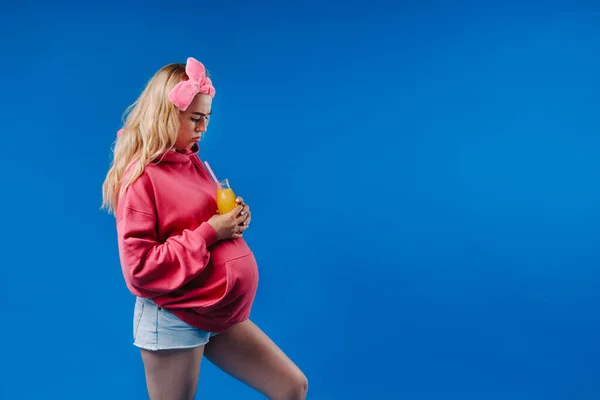 Беременная Девушка Розовой Одежде Бутылкой Сока Синем Фоне — стоковое фото