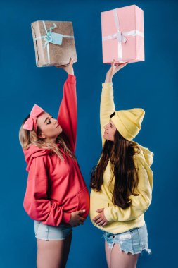 Elinde hediyeler olan iki hamile kız mavi izole bir geçmişleri var..