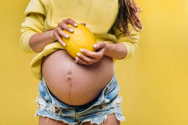 Těhotná Dívka Žlutou Bundou Stojí Melounem Rukou Žlutém Izolovaném Pozadí — Stock fotografie