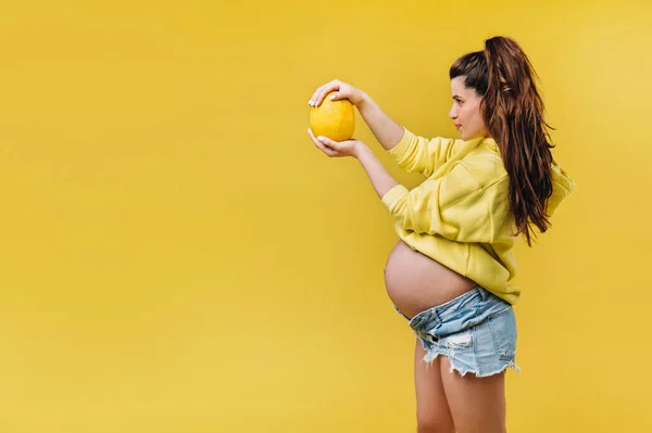 Pregnant Girl Yellow Jacket Stands Melon Her Hands Yellow Isolated — Stock Photo, Image