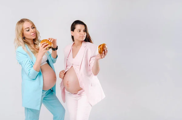 Две Беременные Женщины Костюмах Гамбургерами Руках Сером Фоне — стоковое фото