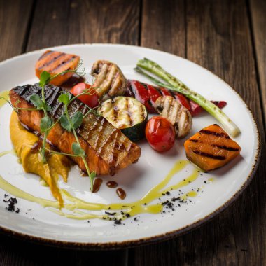 Beyaz tabakta sebzeli ızgara somon.