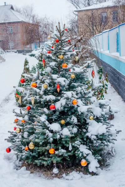 Sokakta karla kaplı yeni yıl ağacı. Noel ağacında asılı oyuncaklar var. Tatil için süslenmiş Noel ağacı.