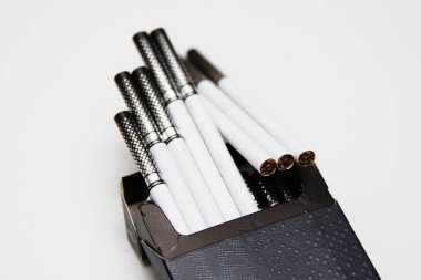 Beyaz arka planda açık bir paket sigara. Sigaraların yarısı paketten çıkarılmış.