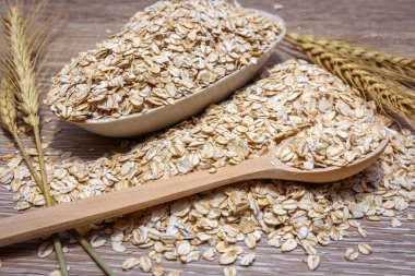 Kaşığın yanında bir kasede yulaf ezmesi. Çuval bezi. Sağlıklı ve sağlıklı bir yiyecek olarak doğal yulaf ezmesi. Yulaf ezmesi diyeti