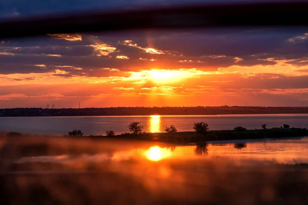 Gölde gün batımı. Arabanın penceresinden batan güneşin görüntüsü. Ada bir gölün ortasındadır. Düşünce ve romantizm için güzel bir gün batımı