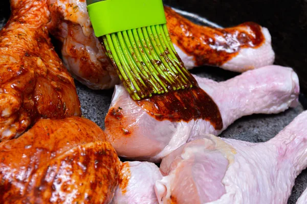 Baharatlı tavuk budu. Aşçının eli fırçayla tavuk etini baharatlarla yayar ve pişirmek için malzemeleri hazırlar..