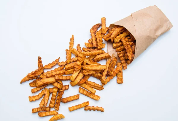 Kese kağıdında kızarmış patates kızartması. Patatesler parçalanıyor. Fast food. Beyaz arkaplanda izole