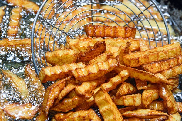 French fries are fried in a deep fat fryer. Checking the dish for readiness. Fast food. French fries are used as a side dish in food.